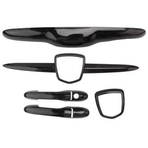 May include: A set of glossy black car exterior accessories, including a rear spoiler, door handles, and emblem surrounds. The parts have a sleek, modern design, and are arranged against a white background.
