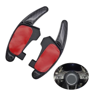 Può includere: Due leve del cambio al volante in fibra di carbonio nera con cuscinetti adesivi rossi sul retro. Le leve hanno una forma curva e allungata e sono mostrate accanto a un'immagine circolare di un volante con le leve installate.