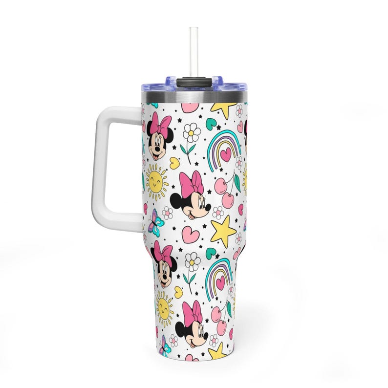 Puede incluir: Un vaso blanco con asa y pajita, con un estampado repetido de Minnie Mouse, arco&iacute;ris, corazones, estrellas, flores y mariposas en rosa, amarillo y azul. El vaso tiene un asa blanca y una tapa azul.