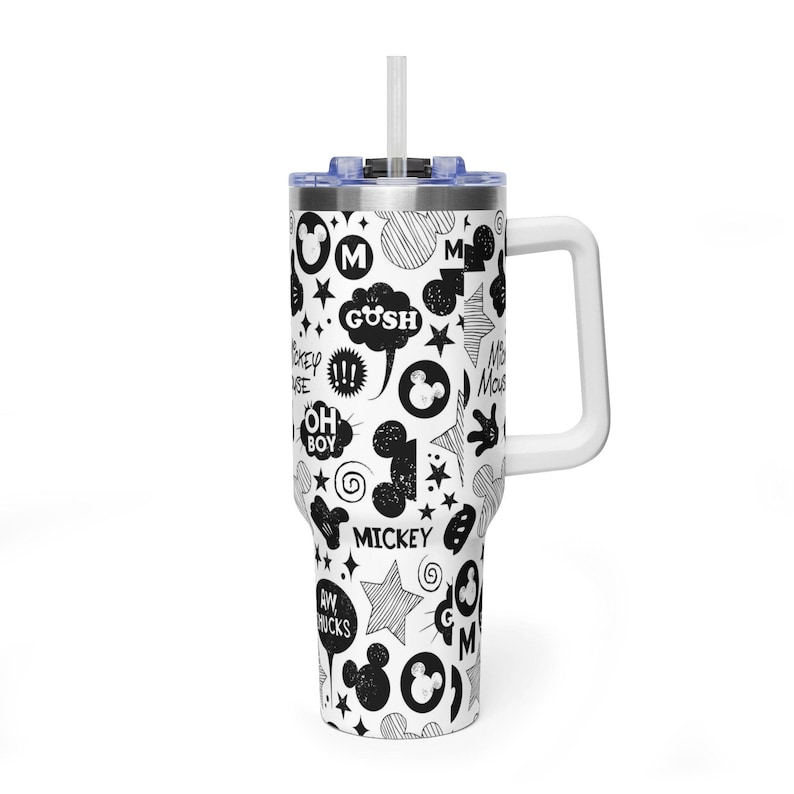 May include: A white tumbler with a black and white Mickey Mouse themed design. The tumbler has a white handle and a blue lid with a white straw. The design includes Mickey Mouse silhouettes, stars, and text like "Gosh" and "Oh Boy".