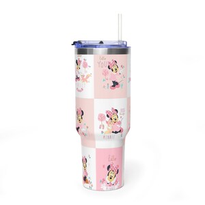 May include: A tall, insulated tumbler with a lid and straw. The tumbler has a repeating pattern of Minnie Mouse in pink and white squares, with the words "Hello", "Perfect", and "Big Hugs".