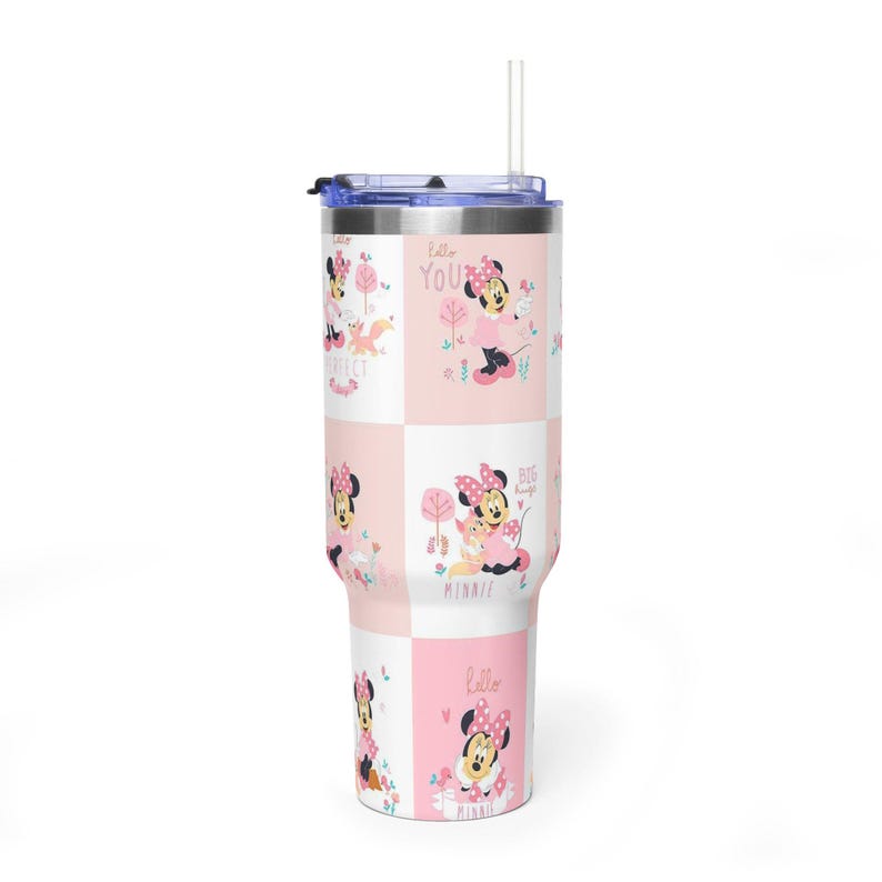 May include: A tall, insulated tumbler with a lid and straw. The tumbler has a repeating pattern of Minnie Mouse in pink and white squares, with the words "Hello", "Perfect", and "Big Hugs".