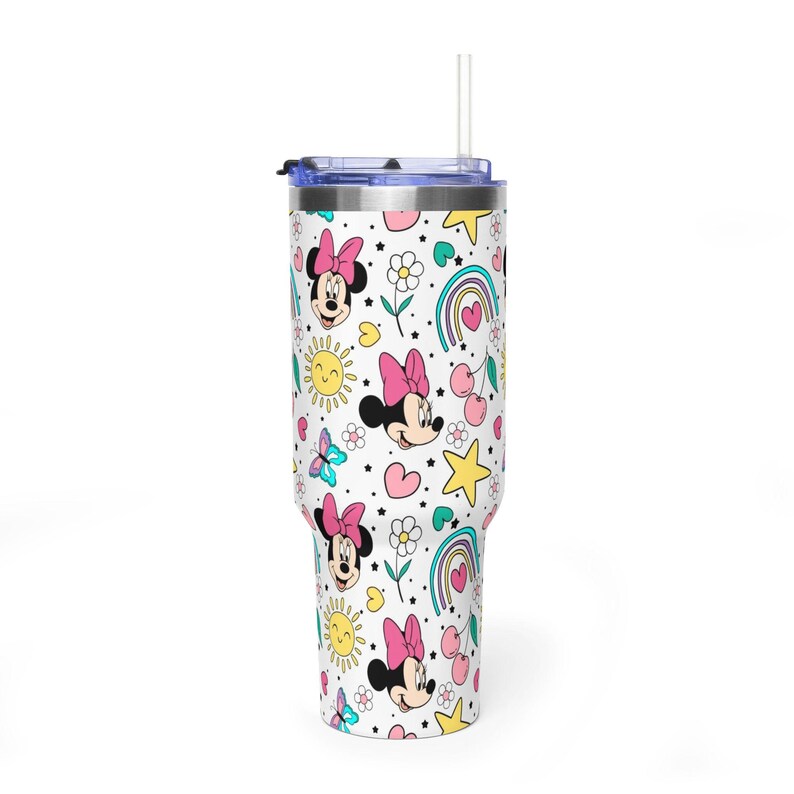 Puede incluir: Un vaso blanco con un patr&oacute;n colorido que presenta a Minnie Mouse, arco&iacute;ris, estrellas, flores, mariposas y corazones. El vaso tiene una tapa azul y una pajita transparente. El dise&ntilde;o es alegre y brillante.