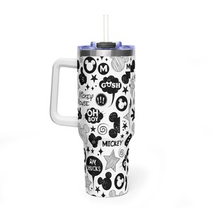 May include: A white tumbler with a black and white Mickey Mouse themed design. The tumbler features a handle, a lid, and a straw. The design includes Mickey Mouse icons, stars, and speech bubbles with phrases like "Gush" and "Oh Boy".
