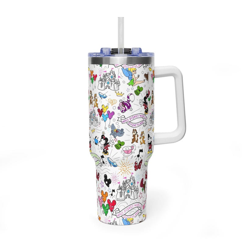 Puede incluir: Taza de viaje blanca con asa y tapa, con un colorido dise&ntilde;o tem&aacute;tico de Disney. El dise&ntilde;o incluye personajes de dibujos animados, castillos y las palabras "Walt Disney World" en un patr&oacute;n repetido. La taza tiene una pajita blanca.