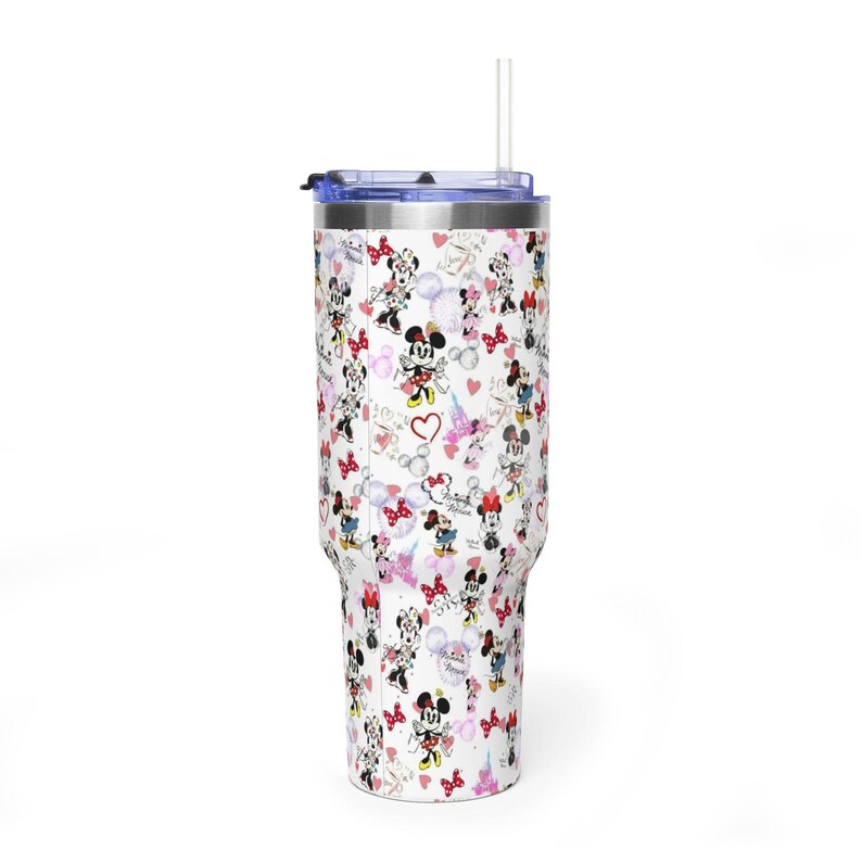 Puede incluir: Un vaso blanco con tapa azul y pajita transparente. El vaso est&aacute; cubierto con un patr&oacute;n de ilustraciones de Minnie Mouse, corazones y la Torre Eiffel. El vaso est&aacute; dise&ntilde;ado para contener aproximadamente 887 ml.