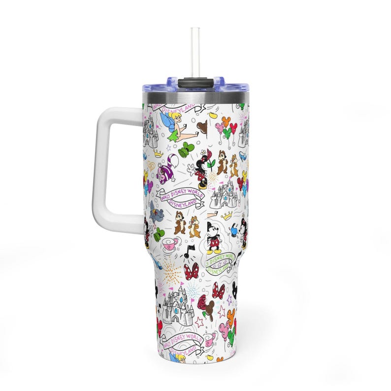 Puede incluir: Vaso de viaje blanco con asa, tapa y pajita. El vaso est&aacute; cubierto con un patr&oacute;n repetido de personajes e iconos de Disney, incluyendo Mickey Mouse, Minnie Mouse y el castillo de Cenicienta. Tambi&eacute;n es visible el texto "Walt Disney World Disneyland".