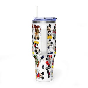 May include: A white stainless steel tumbler with a handle and a clear straw, featuring a repeating pattern of various Mickey Mouse illustrations in different outfits and poses, including a sailor suit, a hoodie, and a green hat, against a white background.