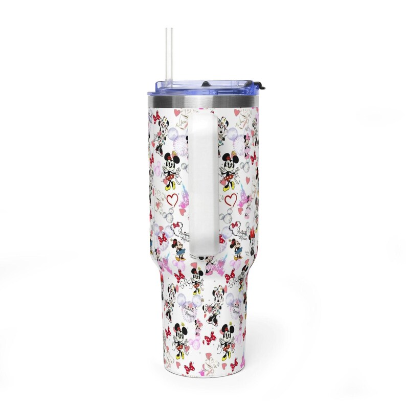 Puede incluir: Un vaso blanco con asa, con un estampado de personajes de Minnie Mouse, corazones y globos. El vaso tiene una tapa azul y una pajita transparente. El dise&ntilde;o incluye detalles en rojo, rosa y negro.