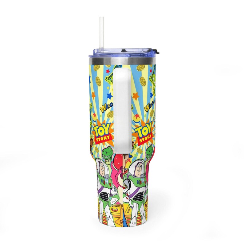 May include: A vibrant tumbler with a design from the film "Toy Story." The design includes Buzz Lightyear, Woody, and other characters, with the words "Toy Story" in a bold font. The tumbler has a white handle and a straw.