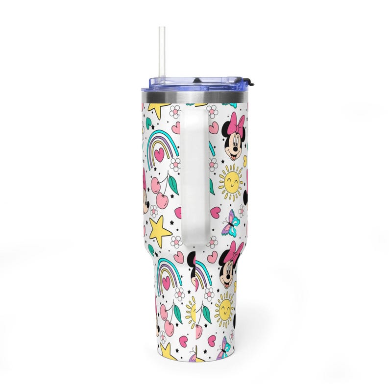 Puede incluir: Vaso blanco con asa, con un colorido estampado de Minnie Mouse, arco&iacute;ris, cerezas, estrellas, corazones, flores y mariposas. El vaso tiene una tapa azul y una pajita transparente.