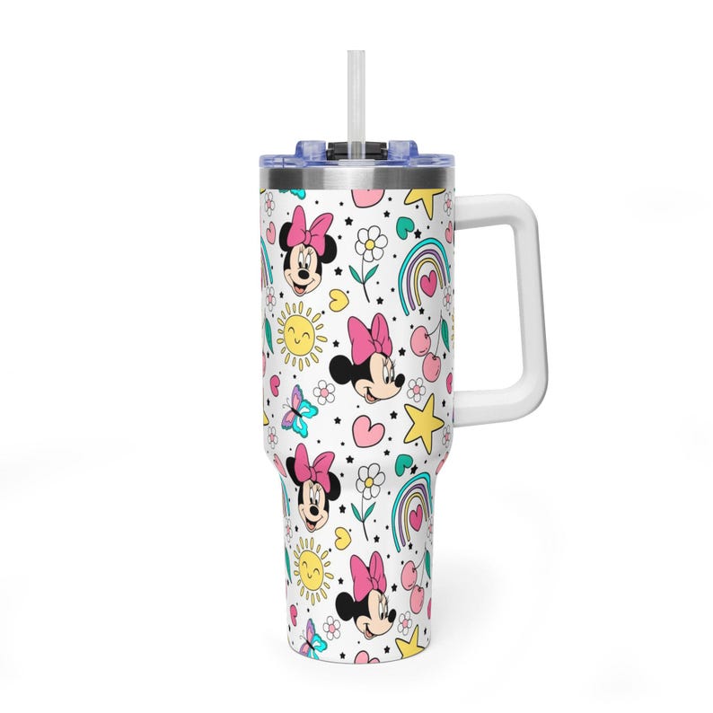 Puede incluir: Un vaso blanco con asa y pajita, con un estampado repetido de Minnie Mouse, arco&iacute;ris, corazones, estrellas, mariposas y flores. El vaso tiene un asa blanca y una tapa azul.