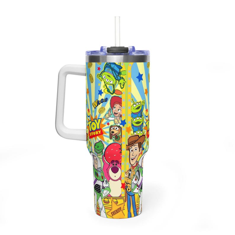 May include: A large, insulated travel mug with a white handle and straw. The mug features a vibrant design with characters from the film "Toy Story", including Woody, Buzz Lightyear, and the Little Green Men. The background has yellow stripes and blue stars.