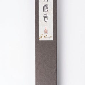 May include: A rectangular, dark brown box with a white label featuring Japanese text in red and black. The box has a minimalist design, suggesting a product related to Japanese culture or wellness.