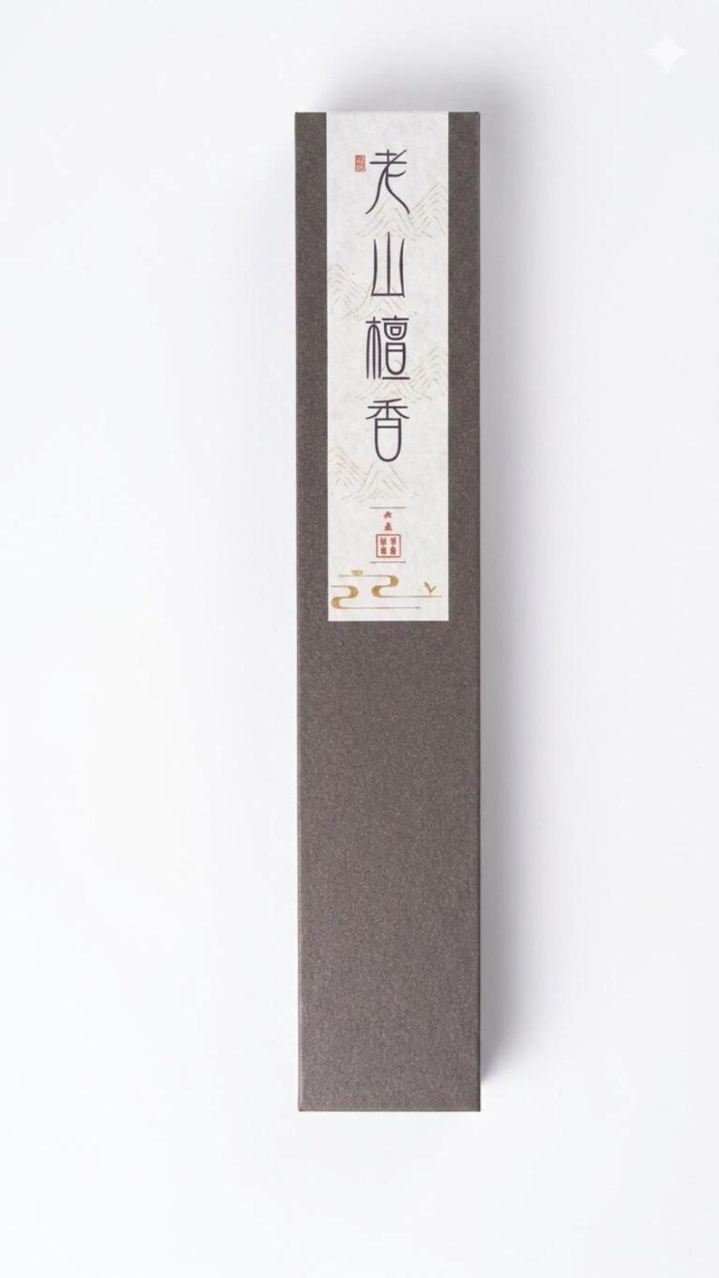 May include: A rectangular, dark brown box with a white label featuring Japanese text in red and black. The box has a minimalist design, suggesting a product related to Japanese culture or wellness.