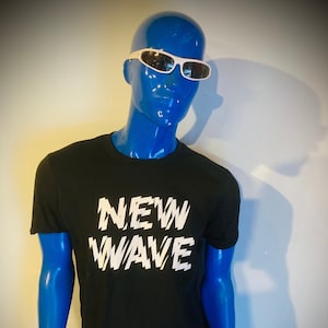 May include: A black t-shirt with a white graphic that says "NEW WAVE" in a stylized font.