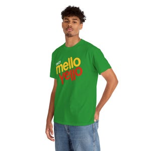 Puede incluir: Una camiseta verde con las palabras "Enjoy Mello Yello" impresas en amarillo y rojo. La camiseta es de manga corta y cuello redondo.