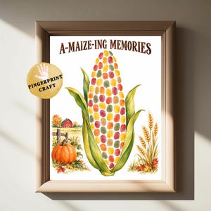 Könnte beinhalten: Ein gerahmter Druck mit einem zentralen Maiskolben aus bunten Fingerabdrücken und dem Text A-MAIZE-ING MEMORIES darüber. Die Szene zeigt eine kleine rote Scheune, einen Kürbis und Weizenähren. Ein kreisförmiges Abzeichen trägt die Aufschrift FINGERPRINT CRAFT.
