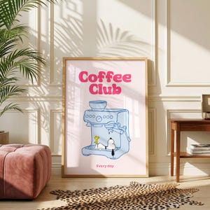 May include: A rectangular wall art print with a light pink background featuring the text Coffee Club in bold pink letters. A blue line drawing of an espresso machine shows Snoopy and Woodstock inside, with the text Every day below.