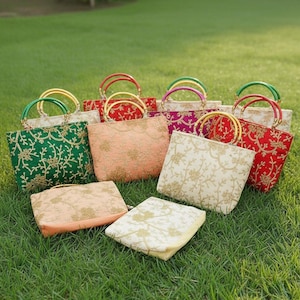 Peut inclure: Plusieurs sacs à main brodés aux couleurs variées, dont vert, pêche, rouge et crème. Chaque sac présente un motif floral et une poignée métallique. Les sacs sont disposés sur un lit d'herbe verte.