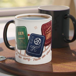 May include: A white ceramic mug featuring a film-themed graphic with three rectangular tiles in green, blue, and red, displaying icons of a director chair, film reel with scissors, and a clapperboard, with the text "Tell the story, Trust the draw".