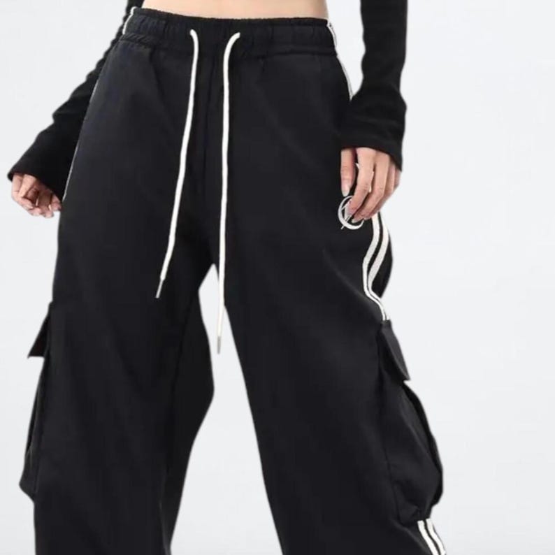 Baggy Cargo Pants | Casual Wide Leg Joggers | Modern Y2K Streetwear 

Woman wearing black baggy cargo pants with wide leg fit and side stripe detail styled for Y2K streetwear fashion.