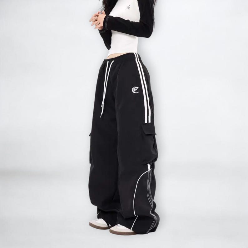Baggy Cargo Pants | Casual Wide Leg Joggers | Modern Y2K Streetwear 

Woman wearing black baggy cargo pants with wide leg fit and side stripe detail styled for Y2K streetwear fashion.