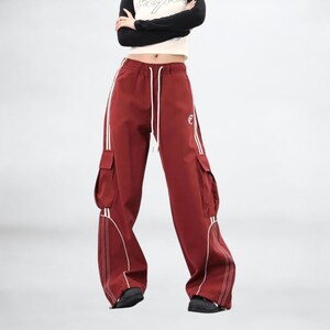 Baggy Cargo Pants | Casual Wide Leg Joggers | Modern Y2K Streetwear 

Woman wearing black baggy cargo pants with wide leg fit and side stripe detail styled for Y2K streetwear fashion.