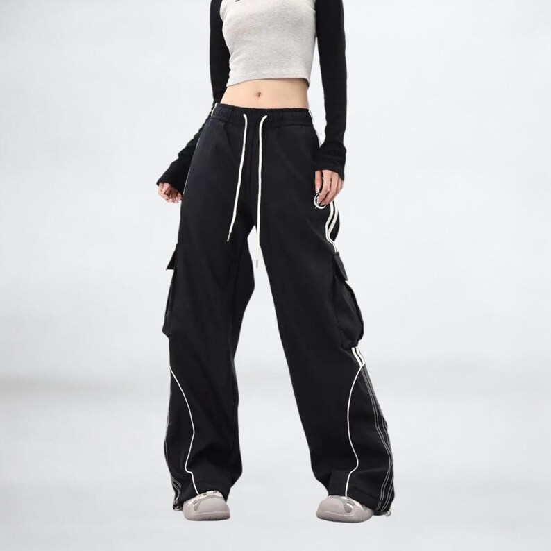 Baggy Cargo Pants | Casual Wide Leg Joggers | Modern Y2K Streetwear 

Woman wearing black baggy cargo pants with wide leg fit and side stripe detail styled for Y2K streetwear fashion.