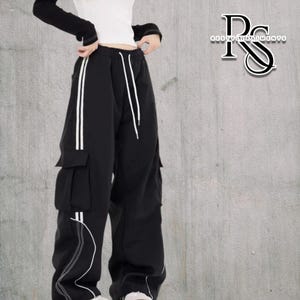 Baggy Cargo Pants | Casual Wide Leg Joggers | Modern Y2K Streetwear 

Woman wearing black baggy cargo pants with wide leg fit and side stripe detail styled for Y2K streetwear fashion.