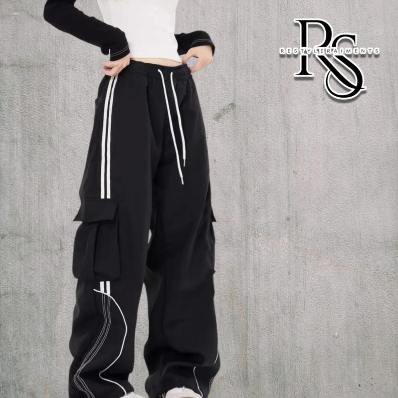 Baggy Cargo Pants | Casual Wide Leg Joggers | Modern Y2K Streetwear 

Woman wearing black baggy cargo pants with wide leg fit and side stripe detail styled for Y2K streetwear fashion.