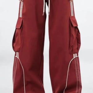 Baggy Cargo Pants | Casual Wide Leg Joggers | Modern Y2K Streetwear 

Woman wearing black baggy cargo pants with wide leg fit and side stripe detail styled for Y2K streetwear fashion.