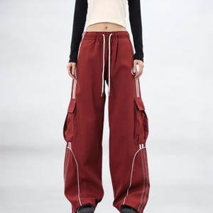 Baggy Cargo Pants | Casual Wide Leg Joggers | Modern Y2K Streetwear 

Woman wearing black baggy cargo pants with wide leg fit and side stripe detail styled for Y2K streetwear fashion.