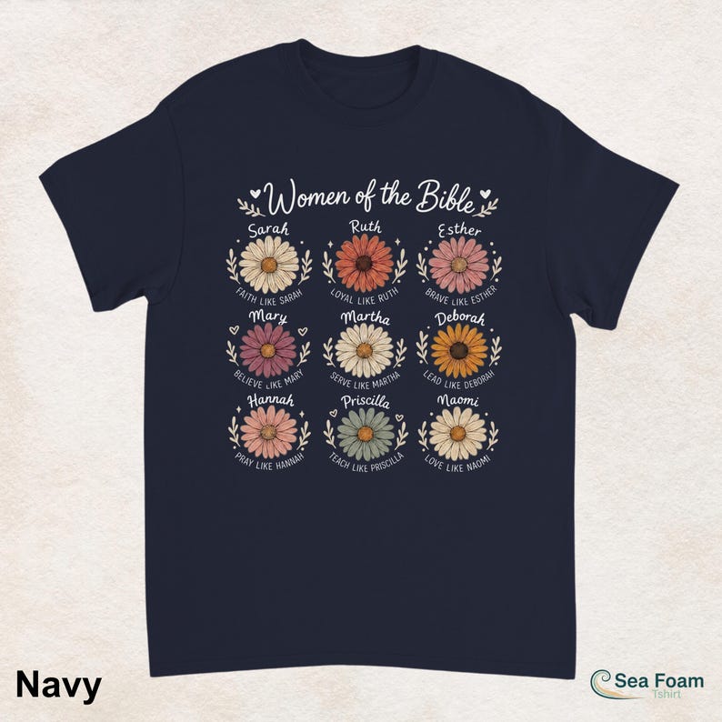 May include: Navy blue t-shirt featuring the text "Women of the Bible" above nine daisy flower designs. Each flower has a name and a related phrase. The shirt is a comfortable, casual wear item.