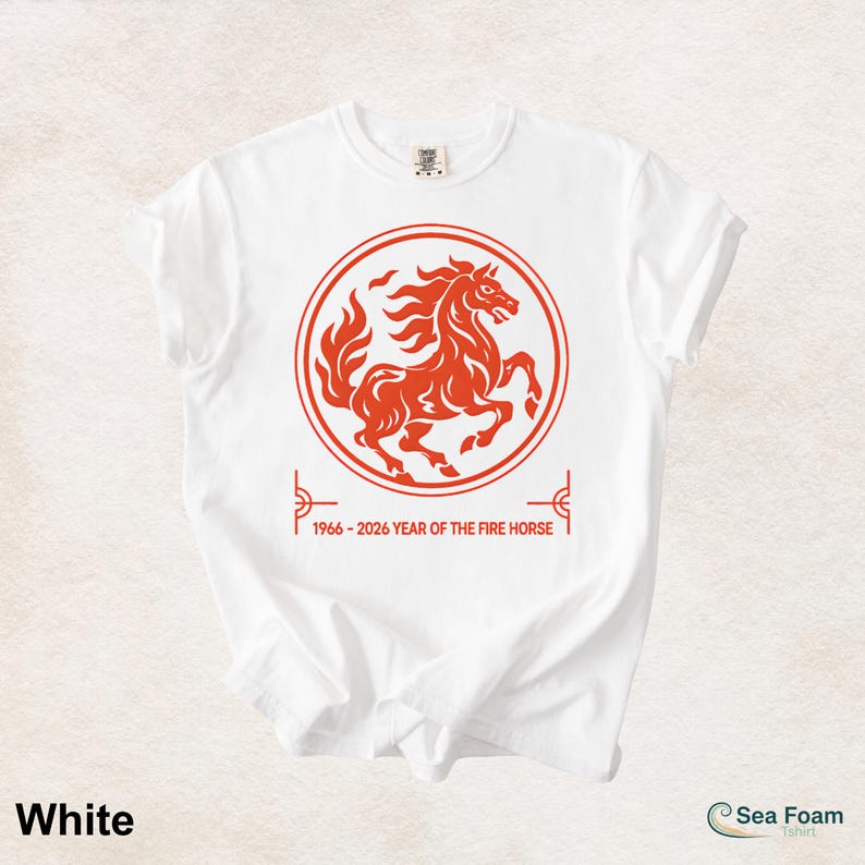 May include: A white short-sleeved t-shirt featuring a red circular graphic of a rearing horse. Below the circle, the text reads 1966 - 2026 YEAR OF THE FIRE HORSE, framed by two small red linear corner accents on the left and right sides of the text.