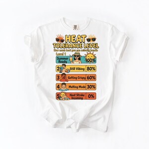 May include: White t-shirt with a graphic that reads "HEAT TOLERANCE LEVEL." The graphic shows a heat level scale with illustrations and percentages, including "Summer Ready" at 100% and "Heat Stroke Incoming" at 0%.