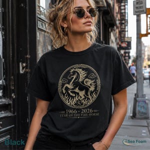 May include: Black t-shirt featuring a circular design with a horse illustration, flames, and text. The text reads "1966-2026 YEAR OF THE FIRE HORSE." The shirt is a crew neck style.