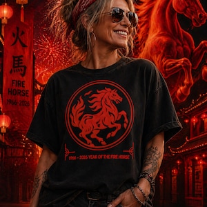 May include: Black t-shirt with a red circular graphic of a prancing horse. The text "FIRE HORSE 1966-2026" is on the shirt and on a banner in the background. The shirt is part of a collection celebrating the Year of the Fire Horse.