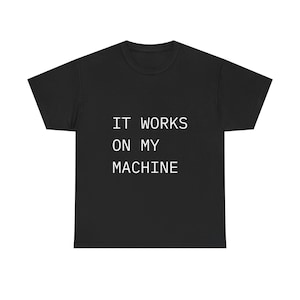 Peut inclure: T-shirt noir avec le texte blanc "IT WORKS ON MY MACHINE". Le t-shirt a un col rond et des manches courtes. Le texte est centré sur le devant du t-shirt.