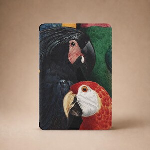 May include: A rectangular tablet case featuring a detailed illustration of two parrots. A large black parrot with a dark beak and red facial patch is positioned above a smaller red and white parrot with a light-colored beak against a green background.