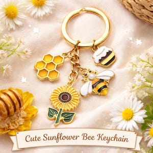 May include: Gold-tone keychain with bee and sunflower charms. The charms include a honeycomb, a bee, a sunflower, and a honey pot. The keychain has the text "Cute Sunflower Bee Keychain" on a banner.