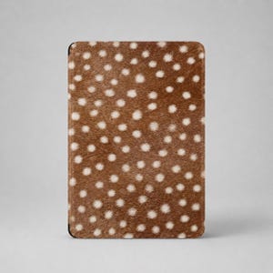 May include: A rectangular tablet or e-reader case featuring a textured brown surface with a repeating pattern of small, off-white circular spots. The cover has a soft, fur-like appearance with rounded corners and a slim, flat profile.