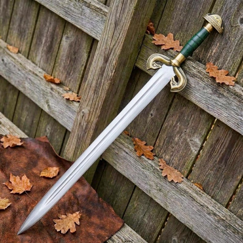 Peut inclure: Une &eacute;p&eacute;e en acier &agrave; double tranchant dot&eacute;e d'une longue lame effil&eacute;e avec une goutti&egrave;re centrale. La poign&eacute;e comprend une prise vert fonc&eacute;, un pommeau en laiton et une garde avec des quillons en laiton courb&eacute;s et orn&eacute;s.