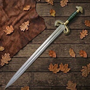 Peut inclure: Une &eacute;p&eacute;e longue dot&eacute;e d'une lame en acier &agrave; double tranchant, d'une poign&eacute;e cylindrique vert fonc&eacute; et d'une garde en laiton orn&eacute;e de quillons incurv&eacute;s en forme de volutes. Le pommeau est un capuchon en laiton arrondi avec un motif textur&eacute;.