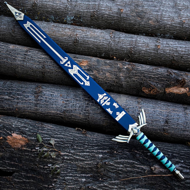 Peut inclure: Une &eacute;p&eacute;e bleue avec une pointe et une garde en m&eacute;tal argent&eacute; en forme d'ailes. La lame est orn&eacute;e de symboles g&eacute;om&eacute;triques blancs, dont un embl&egrave;me triangulaire central. La poign&eacute;e est recouverte d'un rev&ecirc;tement bleu clair et noir.