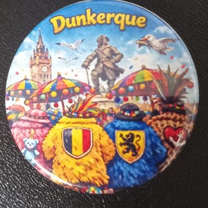 Peut inclure: Un badge rond illustrant le carnaval de Dunkerque. L'image montre une statue, des mouettes et des personnages vêtus de costumes texturés jaunes et bleus avec des écus, sous des parasols multicolores sur fond de ciel bleu avec le texte Dunkerque.