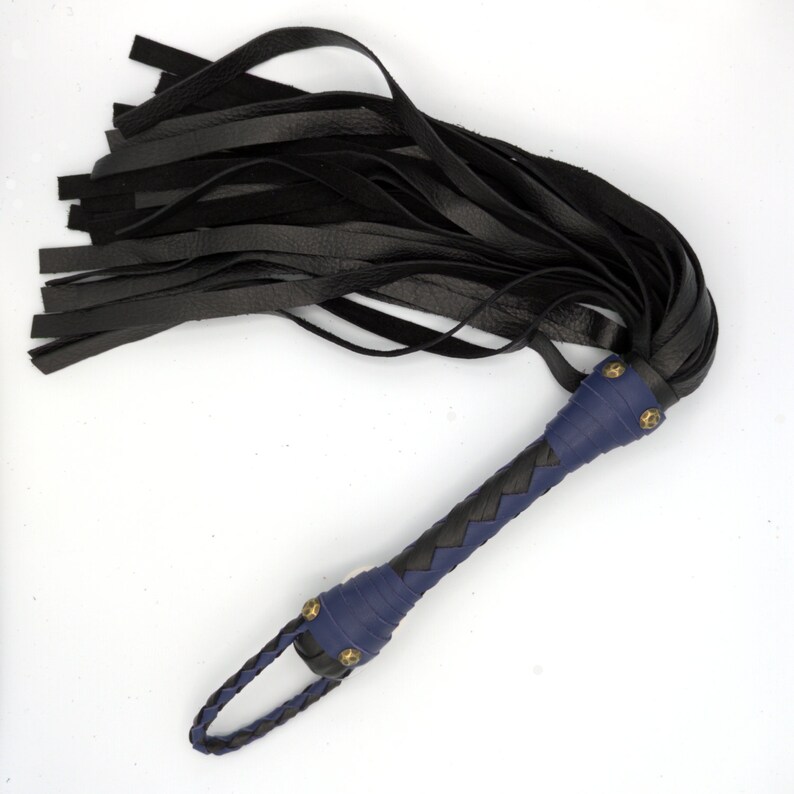 Puede incluir: Un l&aacute;tigo de cuero negro con un mango trenzado azul y detalles en lat&oacute;n.