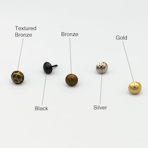 Puede incluir: Cinco clavos de metal con diferentes acabados: bronce texturizado, negro, bronce, plata y oro.