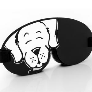 Pu&ograve; includere: Maschera per dormire nera con un viso di cane di cartone animato bianco stampato su di essa. Il cane ha un'espressione felice con gli occhi chiusi e un sorriso.