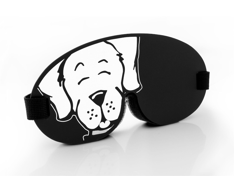 Pu&ograve; includere: Maschera per dormire nera con un viso di cane di cartone animato bianco stampato su di essa. Il cane ha un'espressione felice con gli occhi chiusi e un sorriso.